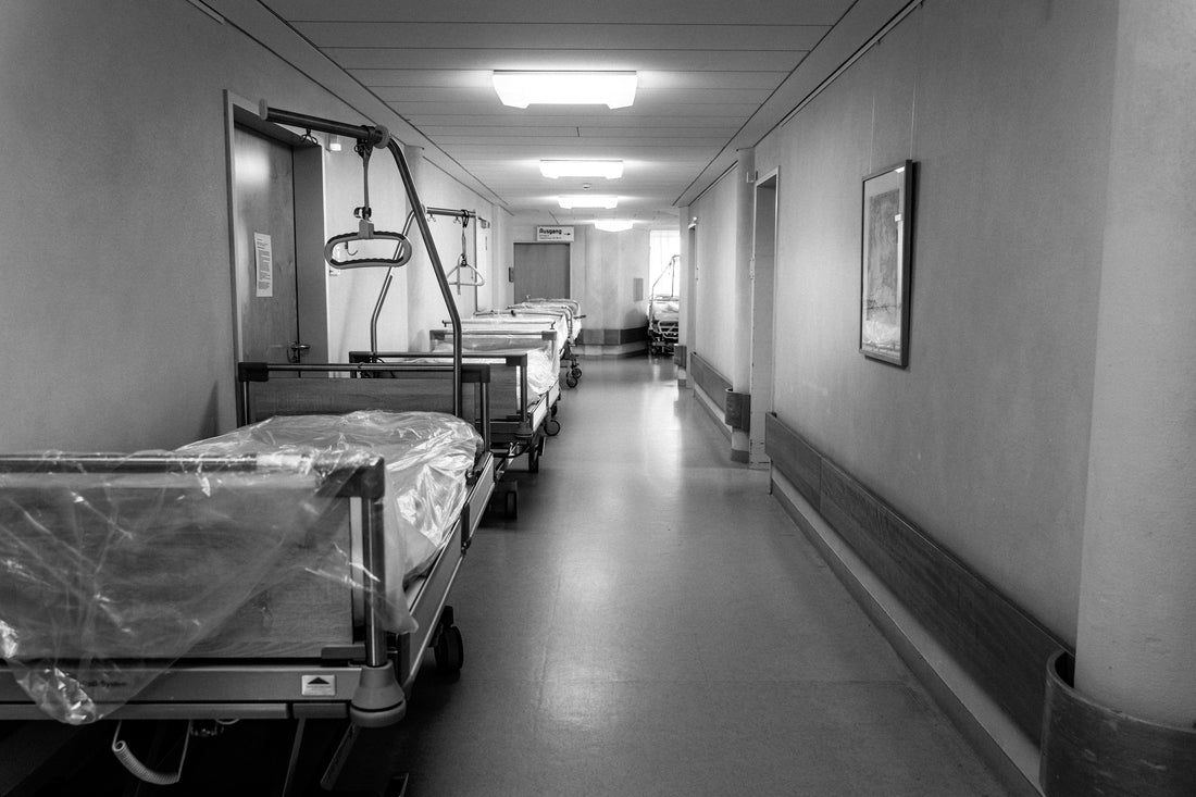 Black-and-white hospital corridor with empty patient beds